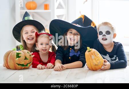 Joyeux frère et trois sœurs pour Halloween. Enfants amusants en costumes de carnaval à l'intérieur. Les enfants gais jouent avec des citrouilles. Banque D'Images