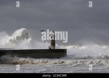 Big White vagues de Piers et phare contre une sombre tempête ciel nuageux. La bouche de la rivière Douro, Porto, Portugal. Banque D'Images