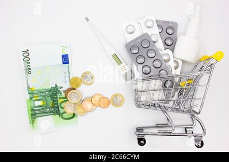 coûts élevés du concept de médicaments coûteux. Une pile de pièces de monnaie et de billets de banque et de nombreuses pilules dans un chariot ou un chariot. Médecine et traitement coûteux Banque D'Images