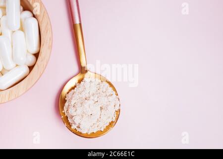 Poudre de collagène et pilules sur fond rose Banque D'Images