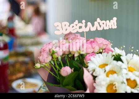 Bouquet de mariage de roses roses avec l'inscription ukrainienne Happy Wedding fait de bois Banque D'Images