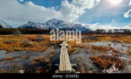 Passerelle sur la rivière avec des montagnes enneigées en arrière-plan en Argentine Banque D'Images