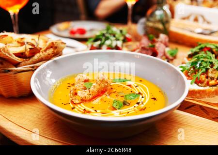 Assiette profonde avec soupe de citrouille et autre nourriture, dîner italien dans un restaurant, tons Banque D'Images