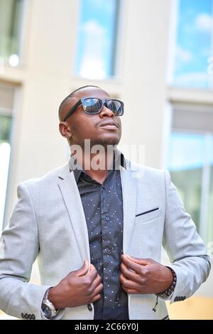 Homme d'affaires afro-américain élégant posant avec des lunettes de soleil. Banque D'Images