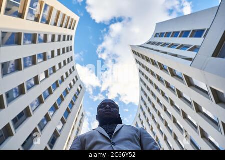 Homme d'affaires afro-américain entre les bâtiments. Il est un achieveur. Banque D'Images