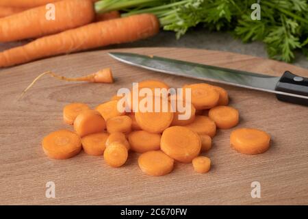 Des tranches de carottes fraîches et crues sur une planche à découper en bois Banque D'Images