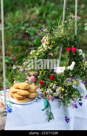 Biscuits sablés au fromage bleu et aux graines de sésame et une couronne de fleurs sauvages sur une balançoire. Style rustique. Banque D'Images