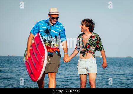 Couple gay s'amusant sur la plage avec jouet gonflable. Banque D'Images