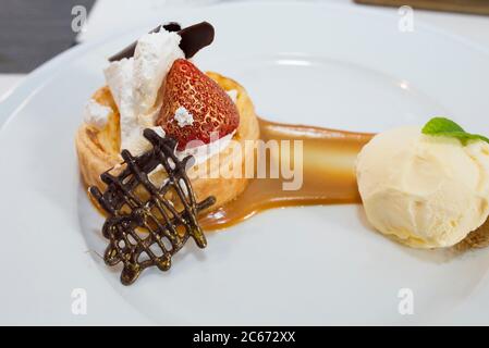 Dessert de haute cuisine recouvert de poussière d'or comestible. Pâte feuilletée à la crème brûlée, aux framboises et aux carreaux de chocolat, recouverte de vanille malgache Banque D'Images