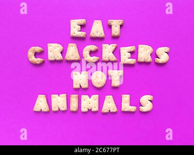 Mangez des craquelins, pas des animaux. Typographie alimentaire sur fond rose. Concept vegan. Photo. Banque D'Images