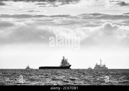 Image en noir et blanc des silhouettes des navires à l'horizon au coucher du soleil. Banque D'Images
