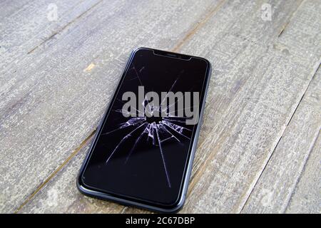 Viersen, Allemagne - juillet 6. 2020: Gros plan de téléphone mobile isolé avec écran en verre fissuré sur table en bois Banque D'Images