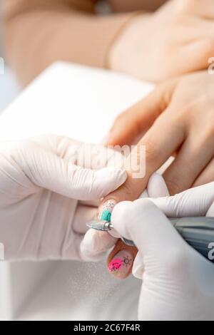 Manucure maître utilise une machine à ongles électrique pour enlever les mains de vernis à ongles dans le salon de manucure Banque D'Images