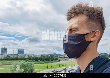 Portrait rapproché d'un homme dans un masque facial de protection à l'extérieur. Homme portant un masque de près en arrière-plan de la ville. Nouvelle normale. Concept de soins de santé pendant la cor Banque D'Images