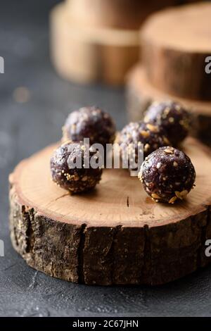 Bonbons végétaliens crus sains. Boules d'énergie faites maison avec sarrasin vert et noix sur une dalle de bois sur fond noir espace de copie Banque D'Images