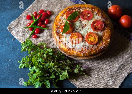 La pizza est une nourriture de mauvaise qualité, mais extrêmement délicieuse et savoureuse. Pizza avec des feuilles de menthe, cerises avec l'utilisation de l'accent sélectif sur un ingrédient particulier Banque D'Images