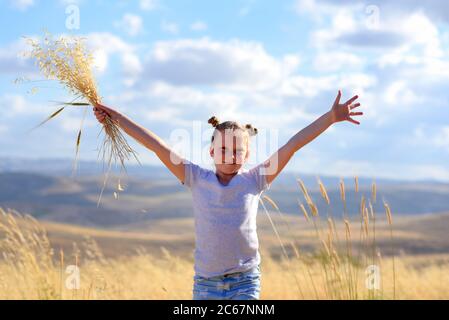 Jeune fille dans un champ célébrant le festival de la récolte d'été de Shavuot. Beauté de la nature, ciel bleu, nuages blancs et champ de blé. Banque D'Images