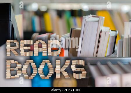 Lire des livres lettres avec un jeune étudiant en choisissant un livre de la tablette dans la bibliothèque en arrière-plan. Banque D'Images