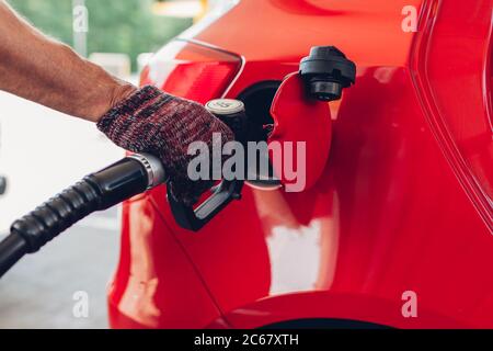 Homme pompant du carburant dans le réservoir de la voiture à la station de remplissage. Un employé de station-service tient le véhicule ravitailleur en carburant par buse. Banque D'Images