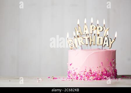 Gâteau d'anniversaire rose avec bougies d'anniversaire dorées Banque D'Images