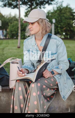 Jeune fille belle tire dans un parc. Contour dans un carnet d'esquisses. Leçon de mise en plan. Banque D'Images