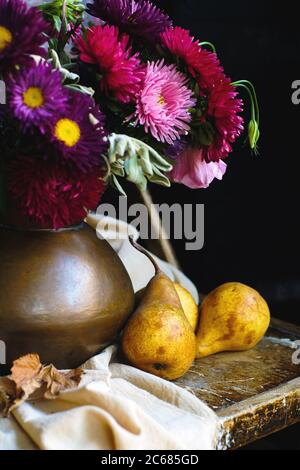 Encore la vie avec des poires et un bouquet de fleurs dans un pot en cuivre sur une table en bois. Banque D'Images