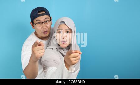 Portait de heureux asiatique couple musulman souriant et pointant vers l'appareil photo, mari et femme embrassant plein d'amour, concept de famille Banque D'Images