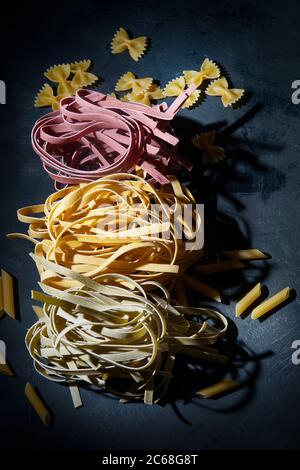 Pâtes italiennes non cuites à base de tagliatelle sur fond noir Banque D'Images