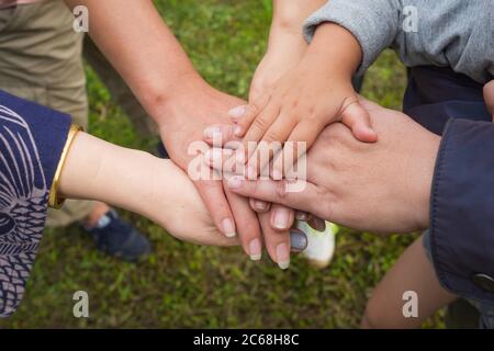 Vue de dessus des jeunes et des enfants qui mettent leurs mains ensemble. Famille avec pile de mains montrant l'unité et le travail d'équipe. Banque D'Images