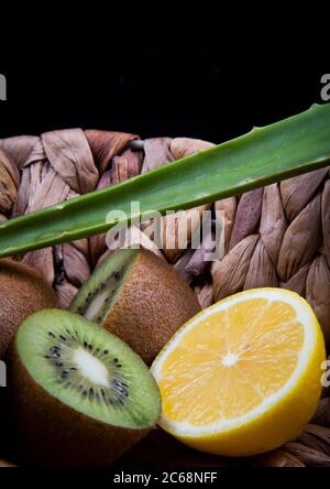 Kiwi et citron aigre et une feuille d'aloe vera dans un panier en bois. Banque D'Images