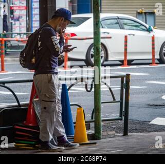 Homme fumant dans une zone réservée à cet effet, Nakameguro, Tokyo, Japon Banque D'Images