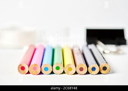 Crayons de couleur arc-en-ciel, trombones et ruban adhésif se trouvent sur une feuille de papier blanche. Articles de papeterie isolés sur fond blanc. Équipement de travail Banque D'Images