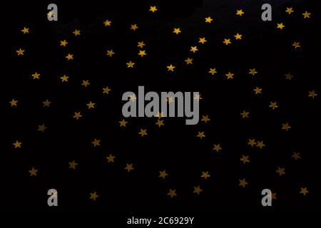 Étoiles dorées sur fond noir. Noël et le nouvel an fond de l'or confetti étoiles. Banque D'Images
