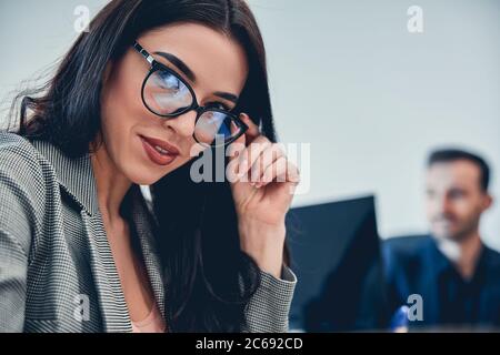 Portrait de jeune belle femme tenant ses lunettes Banque D'Images