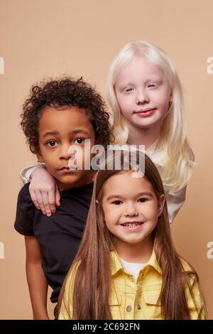 des enfants adorables de différentes nationalités et de couleurs de peau se tiennent ensemble posant à la caméra, groupe de beaux enfants, albinos fille câlin amis. albinisme Banque D'Images