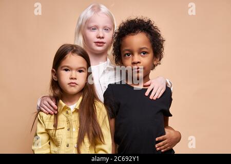 des enfants adorables de différentes nationalités et de couleurs de peau se tiennent ensemble posant à la caméra, groupe de beaux enfants, albinos fille câlin amis. albinisme Banque D'Images