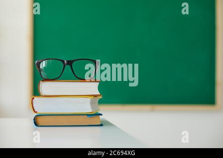 Éducation scolaire. Pile de livres et de lunettes pour enseignants sur le bureau de la salle de classe. Pile de manuels de couverture sur table Banque D'Images