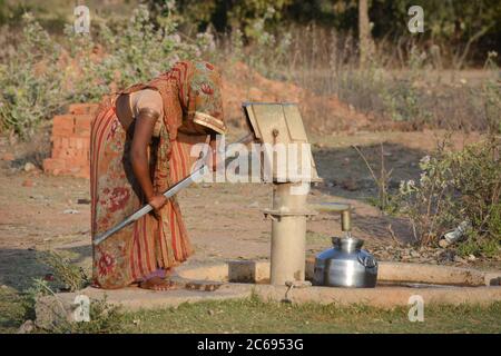 TIKAMGARH, MADHYA PRADESH, INDE - 24 MARS 2020 : femme indienne non identifiée utilisant une pompe manuelle pour l'eau potable. Banque D'Images