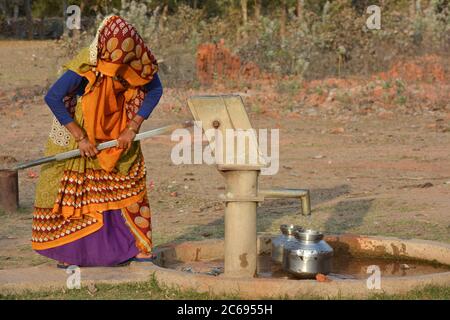 TIKAMGARH, MADHYA PRADESH, INDE - 24 MARS 2020 : femme indienne non identifiée utilisant une pompe manuelle pour l'eau potable. Banque D'Images