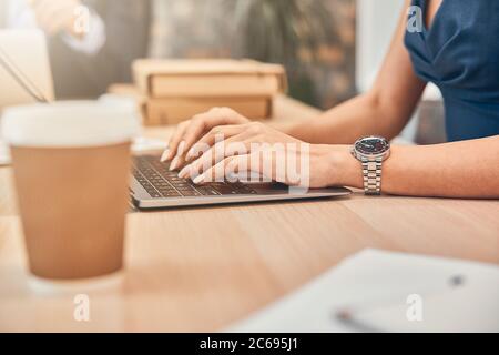 Femme d'affaires portant la montre en main tout en mettant la main sur le clavier Banque D'Images