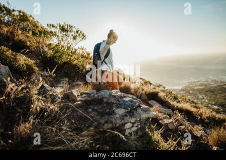 Femme avec sac à dos en train de descendre la montagne. Femme alpiniste qui descend la falaise. Banque D'Images