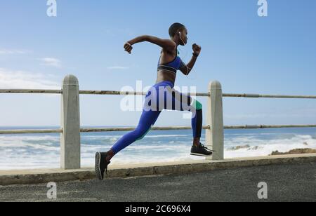 Photo d'une femme sur la route côtière. Le matin, posez une athlète féminine sur la promenade du bord de mer. Banque D'Images