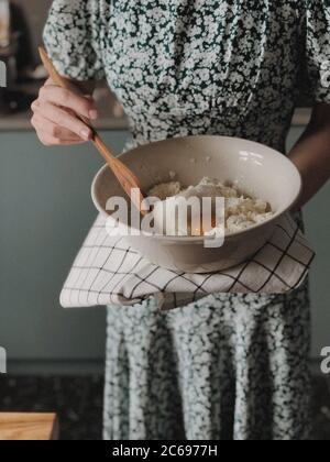 Femme debout dans une cuisine faisant un cheesecake Banque D'Images