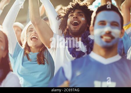 Groupe de fans de football argentins. Les fans de sport enthousiastes lors de la compétition de football en direct scandant et applaudissent pour leur équipe. Banque D'Images