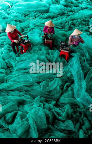 Vue aérienne de trois femmes réparant des filets de pêche, Vietnam Banque D'Images