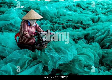 Femme répare des filets de pêche, Vietnam Banque D'Images