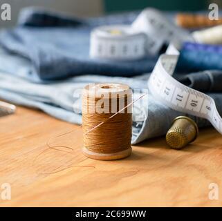 Artisanat, réparation sur mesure. Accessoires de couture fils en gros plan denim table en bois. Cadre horizontal Banque D'Images