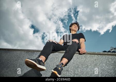 Beau jeune homme assis sous un beau ciel Banque D'Images