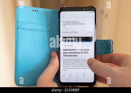 Les mains d'un homme tenant un smartphone avec l'écran montrant un rappel par e-mail du gouvernement britannique pour passer un test de coronavirus Covid-19 Banque D'Images