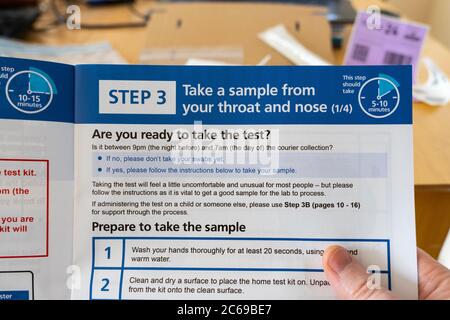 Coronavirus (Covid-19) instructions accompagnant une trousse de test pour effectuer un test à domicile, tenu par les mains d'un homme et lu, Royaume-Uni Banque D'Images